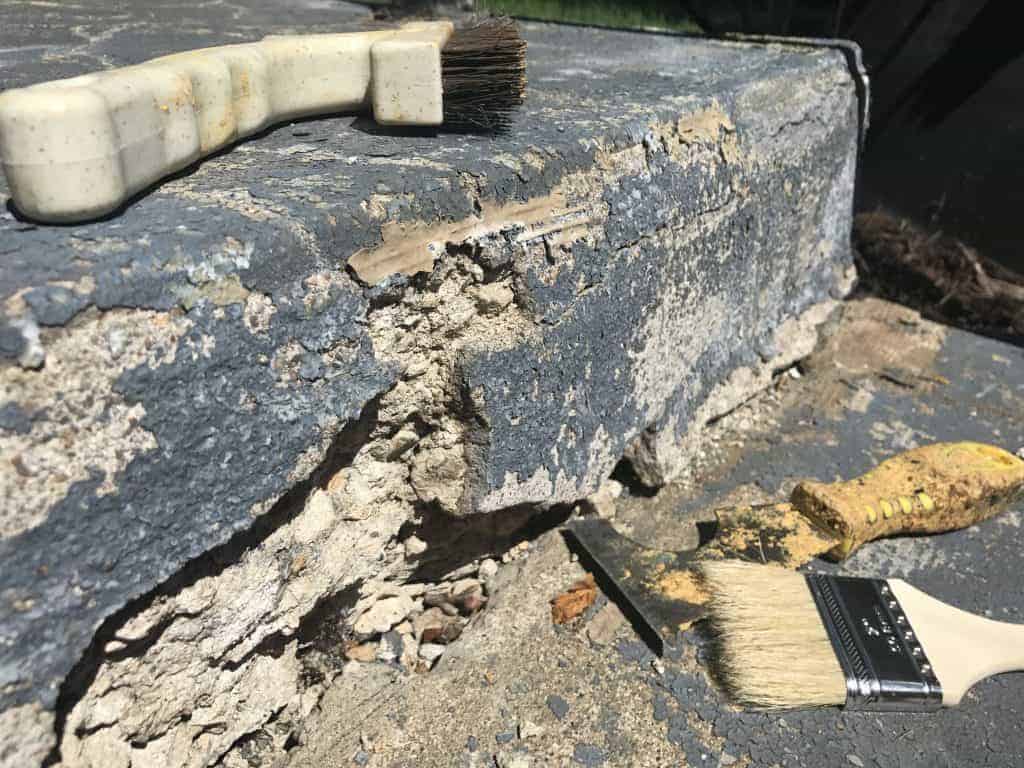 This picture shows a broken, crumbling concrete front step that needs repair. Repairing front porch steps is a simple front yard landscaping tip to improve curb appeal of your home.