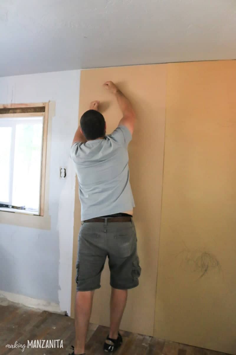 Man pressing MDF sheet onto wall for board and batten accent wall over textured walls