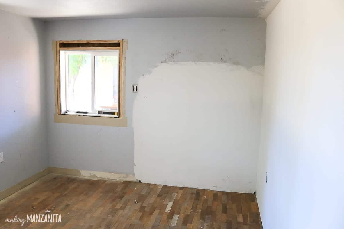 Ugly wall with window missing trim and large patch job in wall where a fireplace used to be