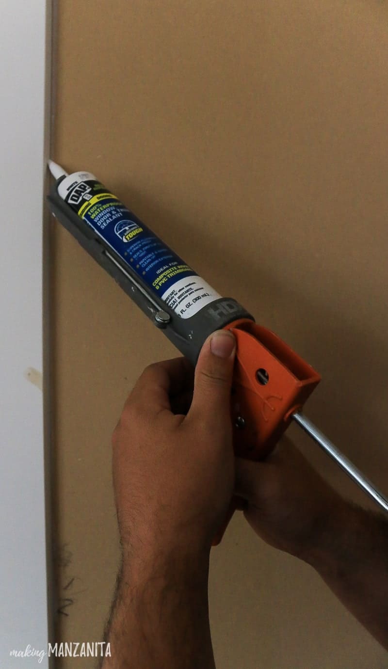 Man adding caulk to board and batten wall seals with caulking gun