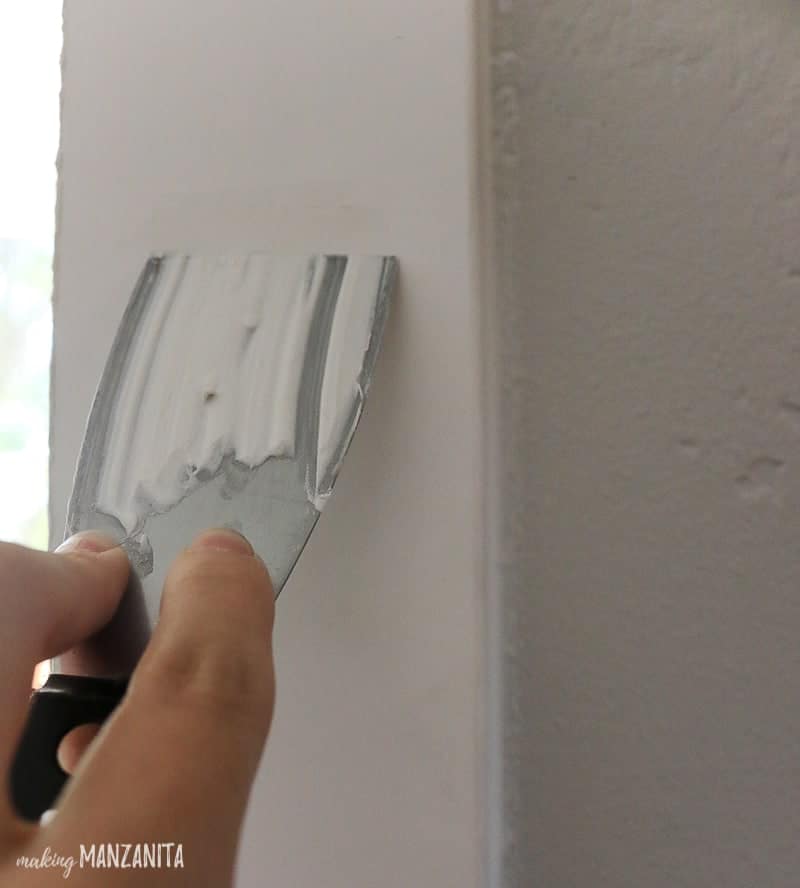 Filling nail holes in trim with spackeling on putty knife 