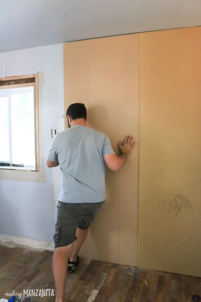 Man pushing MDF panel up and onto a wall 