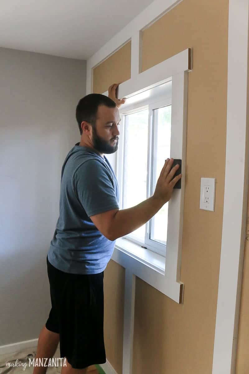 Man sanding trim on board and batten accent wall with sanding block