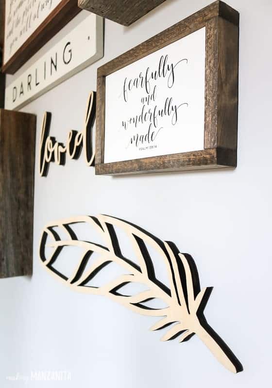A wood feather cut out hanging on a gallery wall