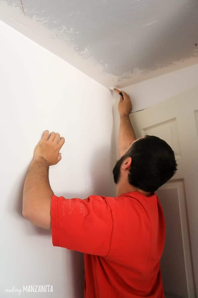 Man painting ceiling corner with paint brush