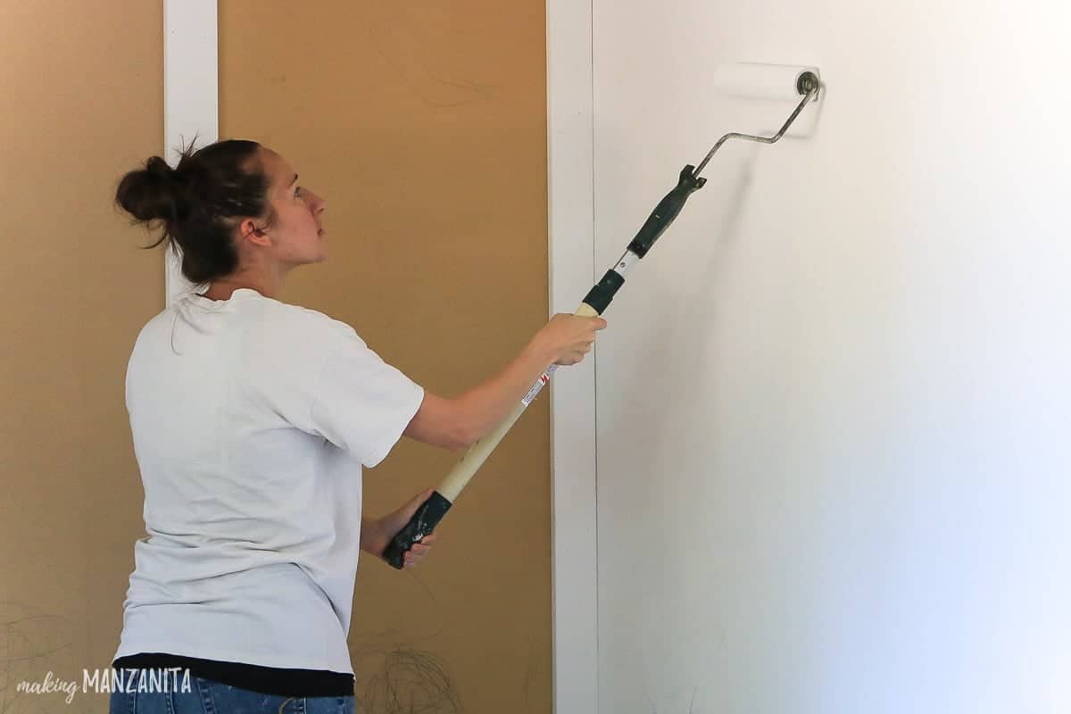 Girl rolling paint on white wall