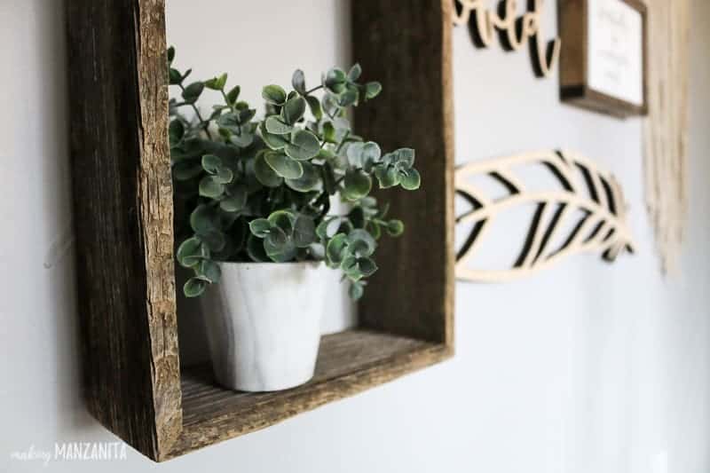 Faux plant on barnwood shelf as part of a baby girl's nursery gallery wall