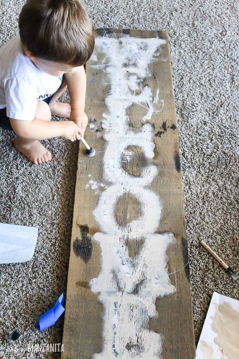 Toddler helping paint welcome sign for front porch