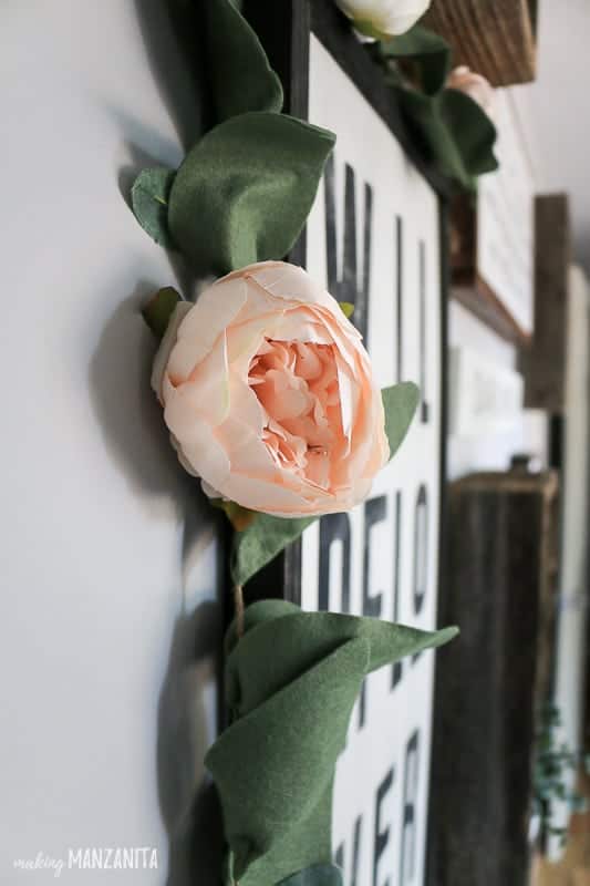 Peony garland hanging on farmhouse sign as part of a gallery wall in a girl's nursery