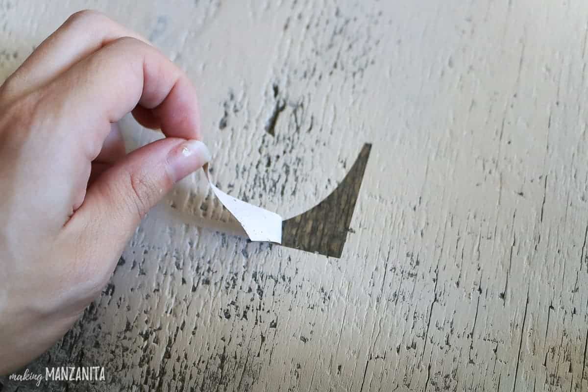 Peeling stencil off of wooden sign with crisp paint lines