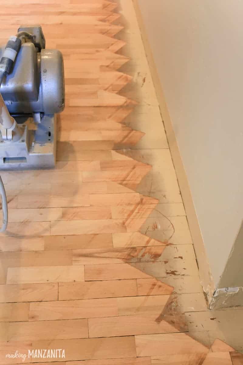 Hardwood floors that have just been sanded diagonally with a floor sander and the edges still need to be sanded. 