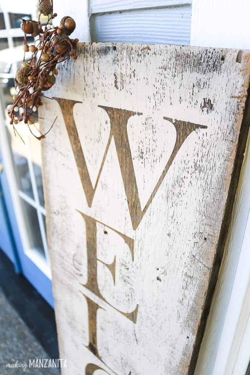 Close up of stenciled letters on rustic wooden sign that says welcome 