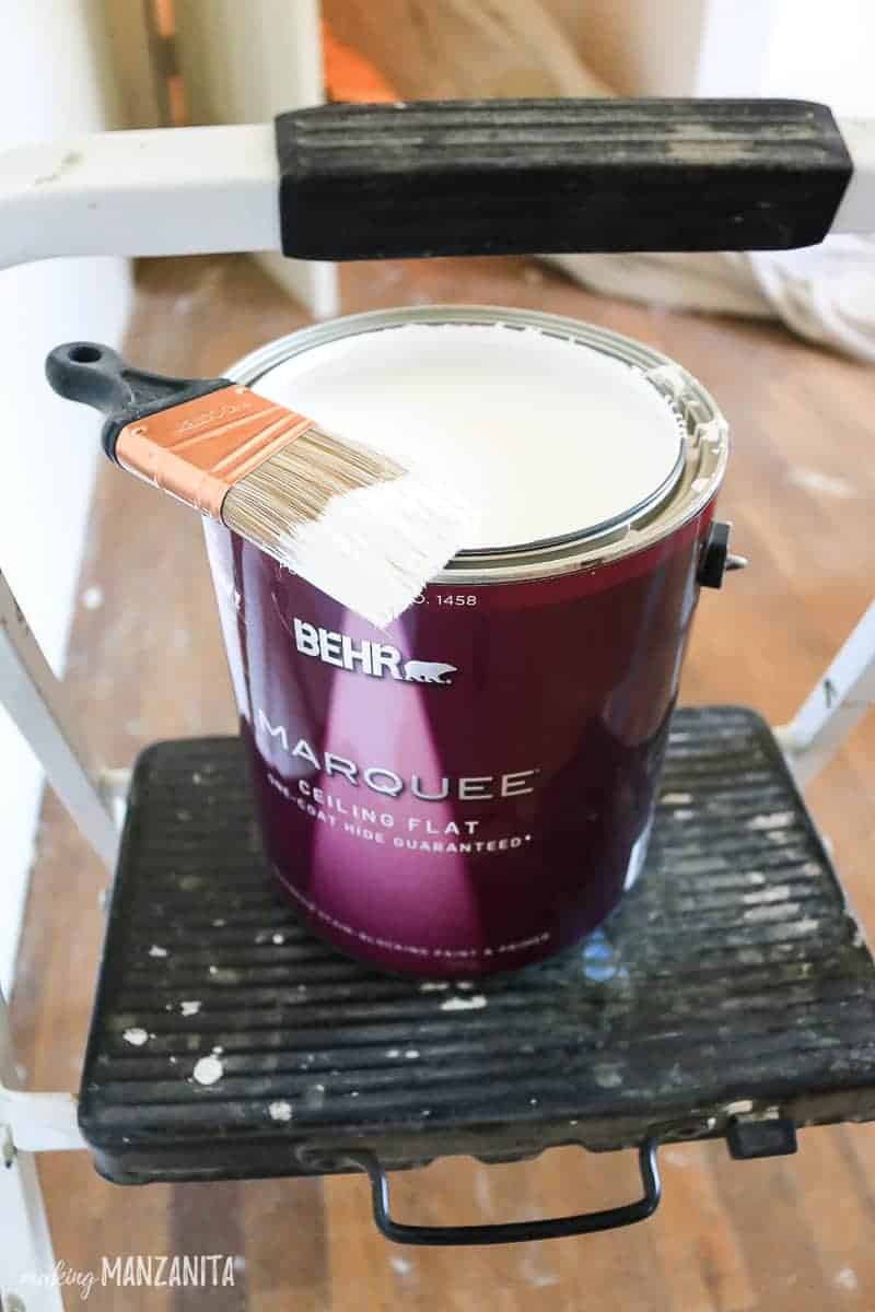 Can of Behr Marquee paint sitting on step stool with an angled sash paint brush 