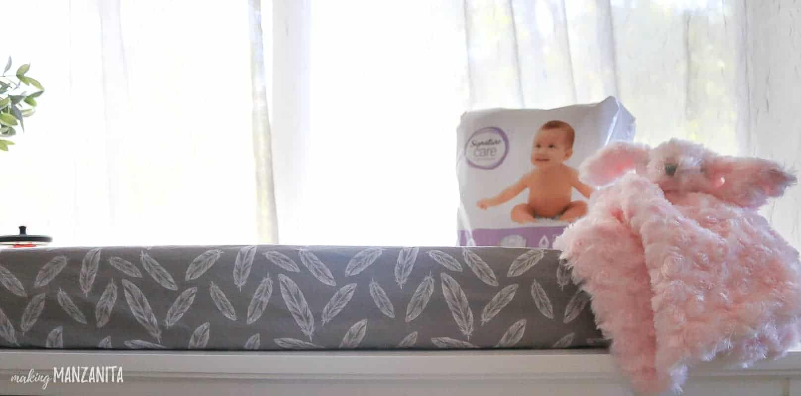 A baby changing pad sitting atop of a changing table dresser, with baby's favorite toy