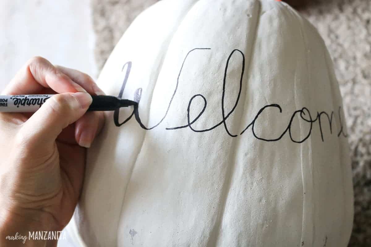 Sharpie writing Welcome on white pumpkin decor