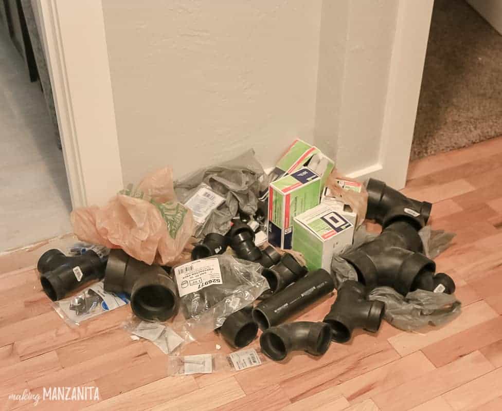 A pile of plumbing supplies used in a bathroom renovation, piled in the hallway. Making piles of renovation supplies makes it easier to stay organized during home renovation projects