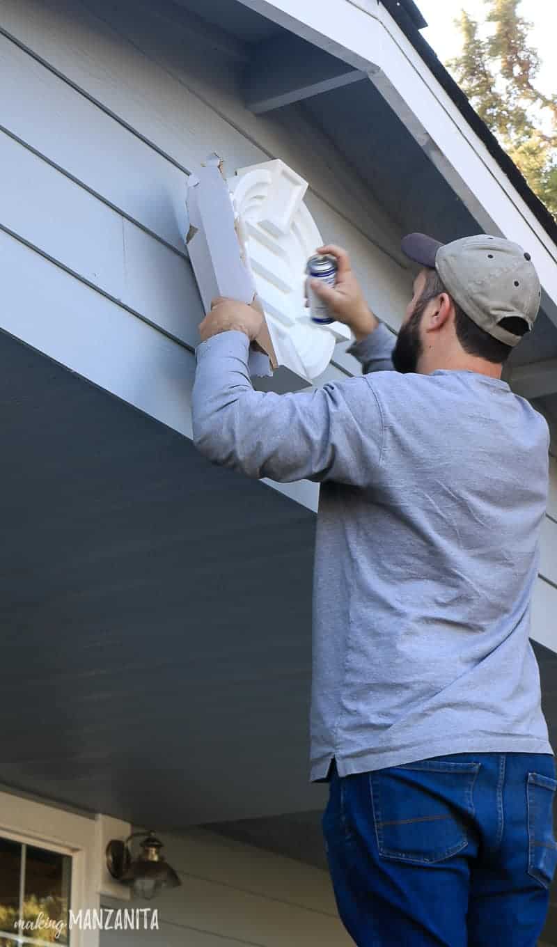 Logan uses white spray paint to touch up the decorative louver which hangs on the front gable of our home.