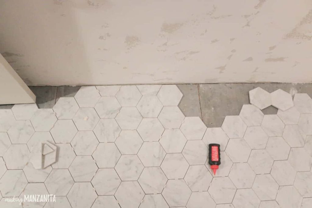 Hexagon marble floor tiles laid out on bathroom floor showing the edges where they need to be cut