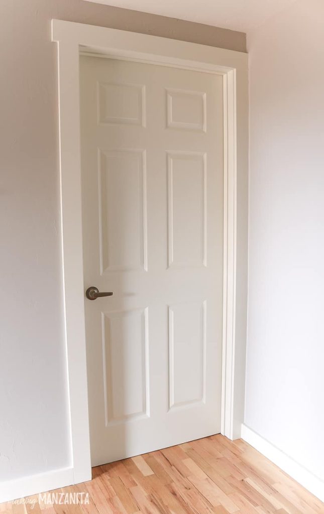 White 6 panel interior door with white trim and gray walls after installing