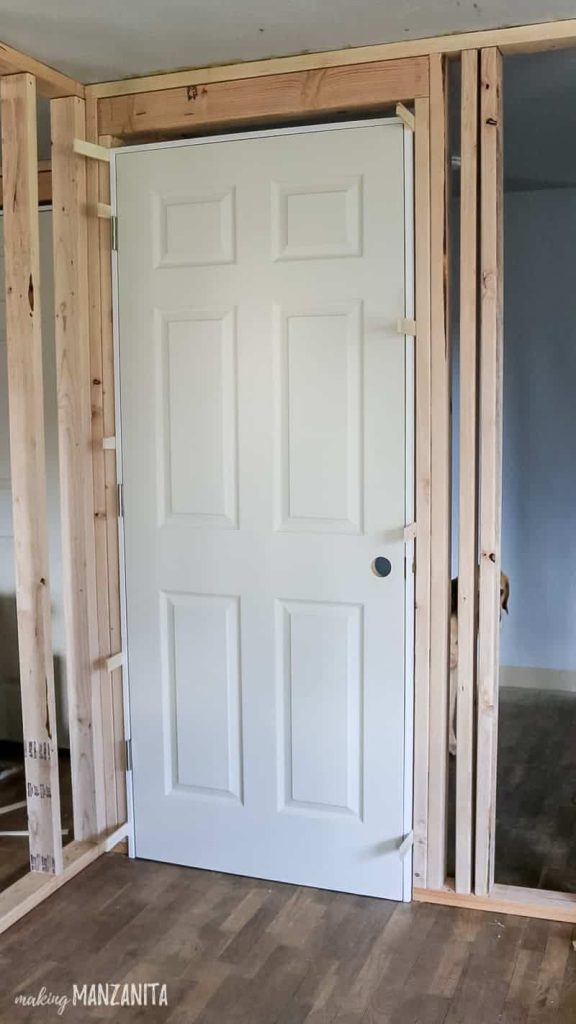 Prehung door being installed in stud wall with wood shims on the sides