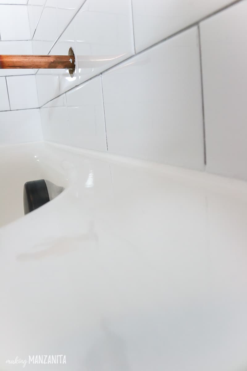 Close up shot of caulk line where the bathtub meets the subway tile wall