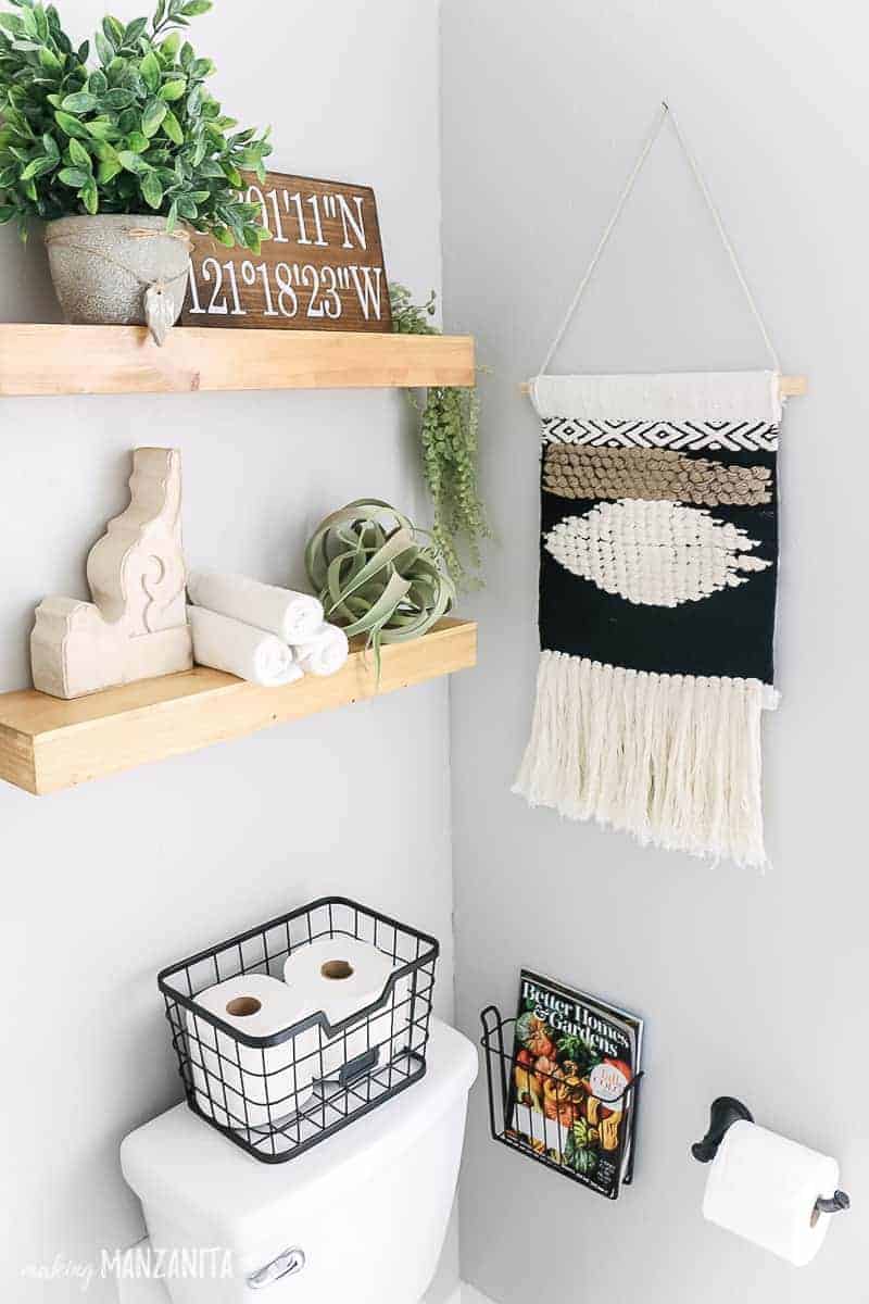 Wood floating shelves over toilet in small bathroom styled with boho farmhouse decor 