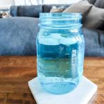 Blue cup of ice water sitting on top of marble tile coaster