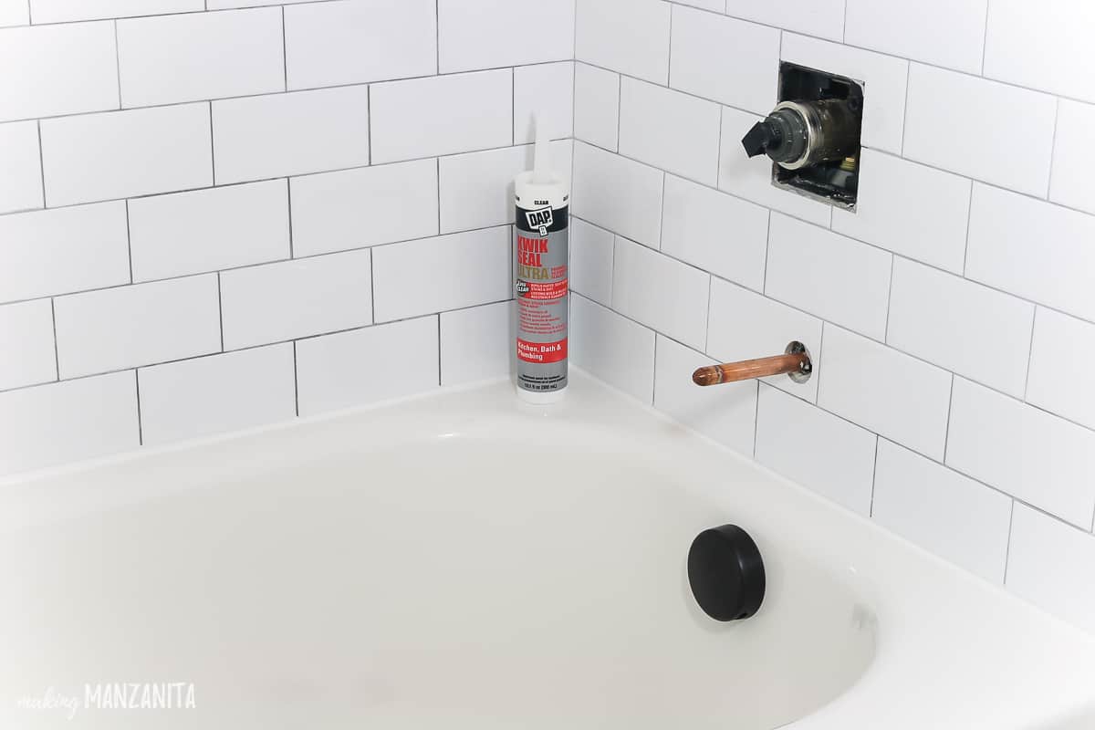 Bottle of DAP Kwik Seal Ultra sitting in the corner of a bathtub / shower 