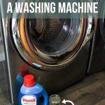 Washing machine beside the washing machine cleaner, vinegar, water and baking soda on the floor with text overlay that says How to Clean a Front Loading Washing Machine