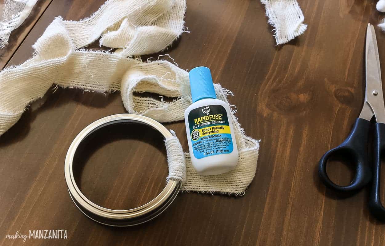 What muslin fabric wrapped around a mason jar lid, radpi fuse glue, and scissors.