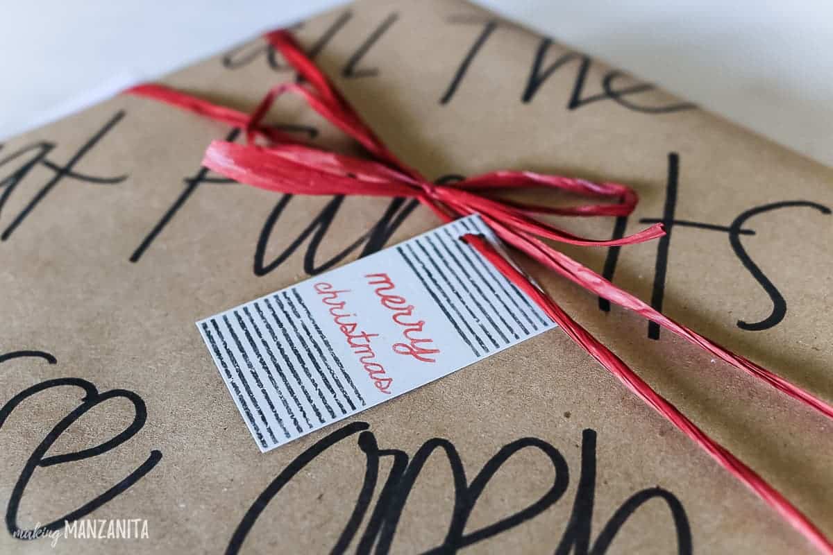 A handmade Christmas gift tag stamped with a custom-made stamp and homemade custom wrapping paper.