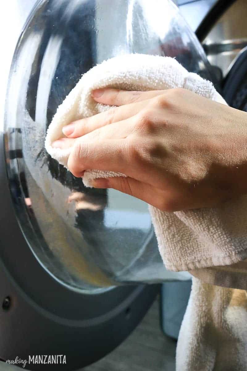 Using a rag dampened with vinegar and water to clean the interior window of my washing machine.