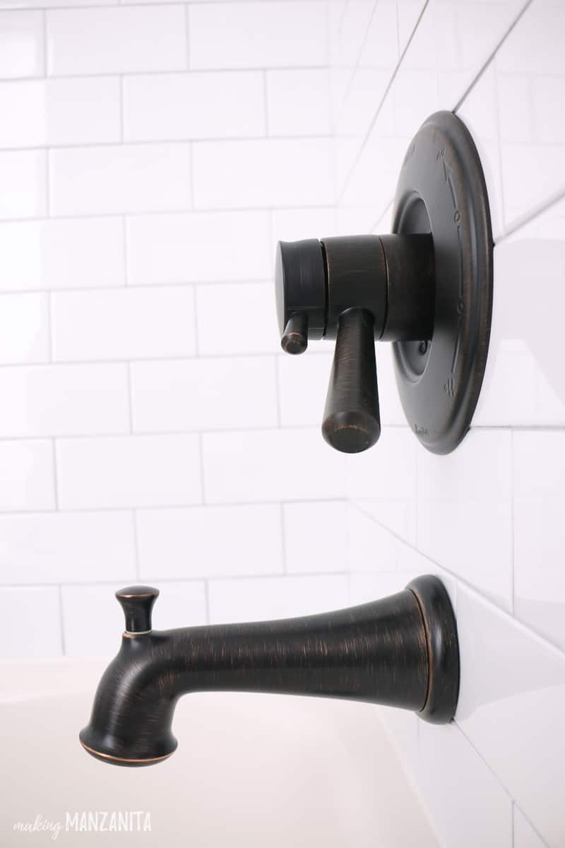 A chic oil rubbed bronze bath tub faucet gives this white farmhouse style bathtub a boho style