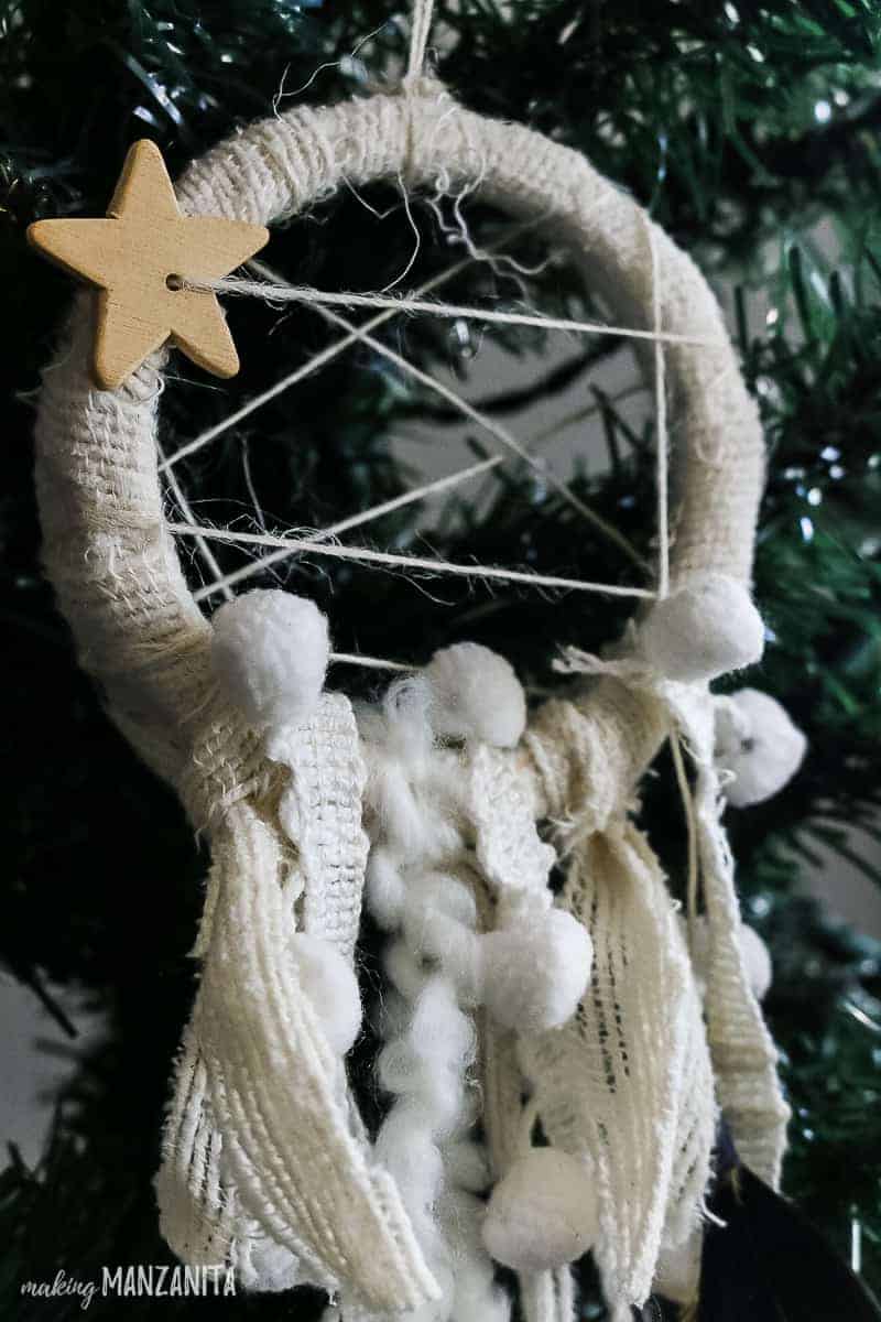 A close up look at the boho dreamcatcher ornament hanging on a christmas tree branch.