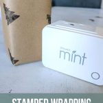 Gift with DIY wrapping paper with stamps sitting next to a stamp machine called with Silhouette mint with text overlay that says stamped wrapping paper for Christmas