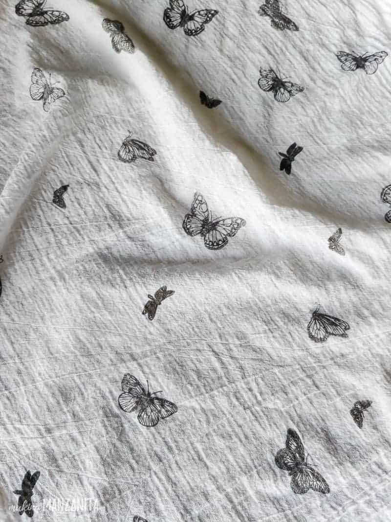 A close up image of a white linen tea towel stamped with small butterfly designs.