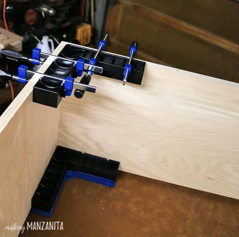 Using the Clamp-It Corner Clamping Jig to clamp together two pieces of wood, forming the corner of our hallway cabinet.