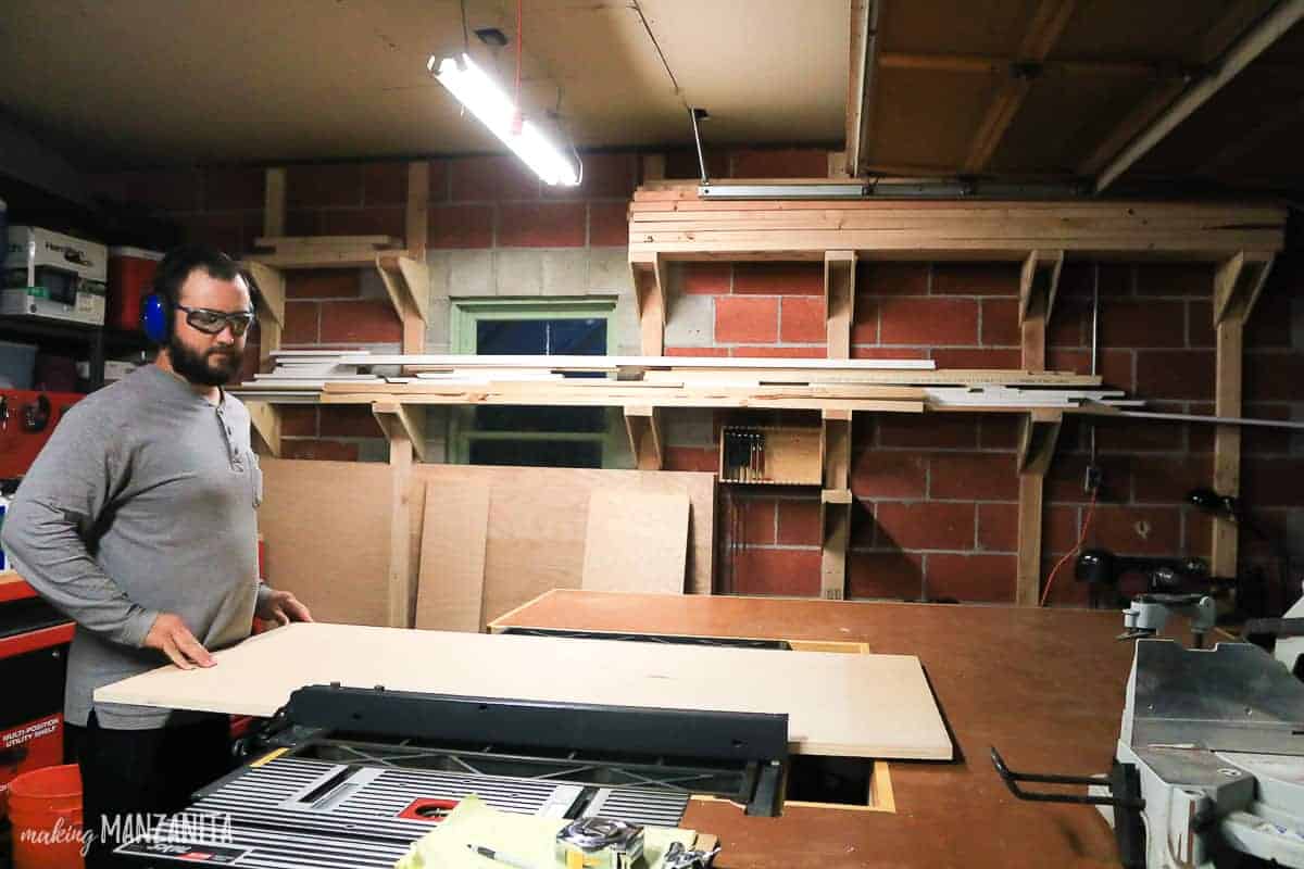 Logan stands at the table saw in our workshop, cutting large slabs of wood to make our new hallway cabinet.