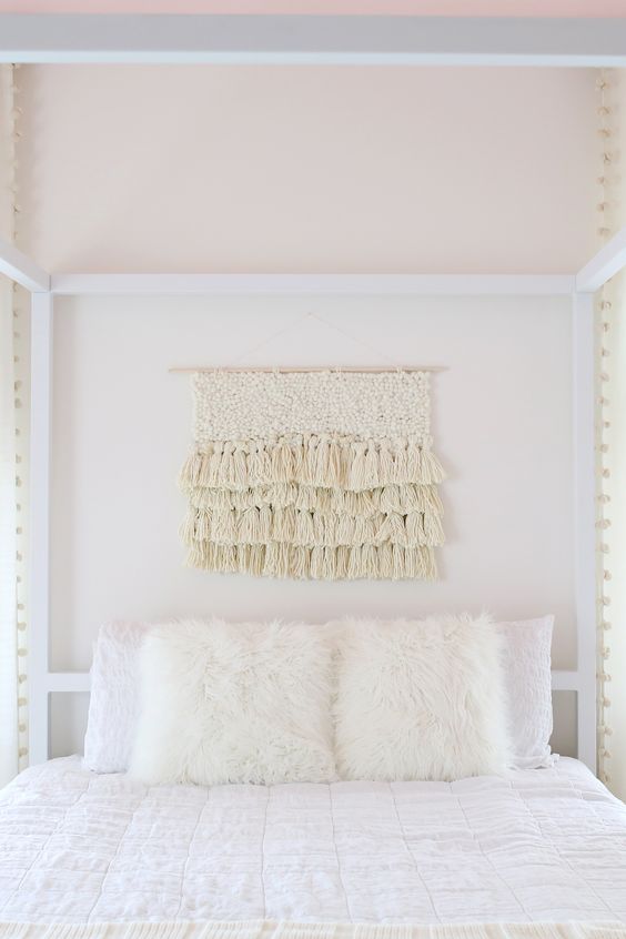 This ivory colored yarn wall hanging with texture and layers of tassels hanging is perfect hanging above this bed as decor