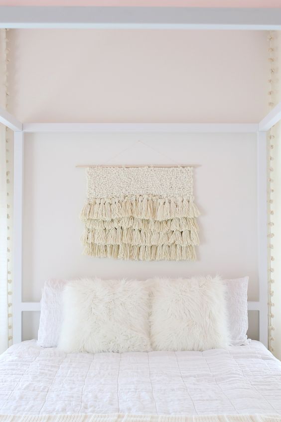 This ivory colored yarn wall hanging with texture and layers of tassels hanging is perfect hanging above this bed as decor 