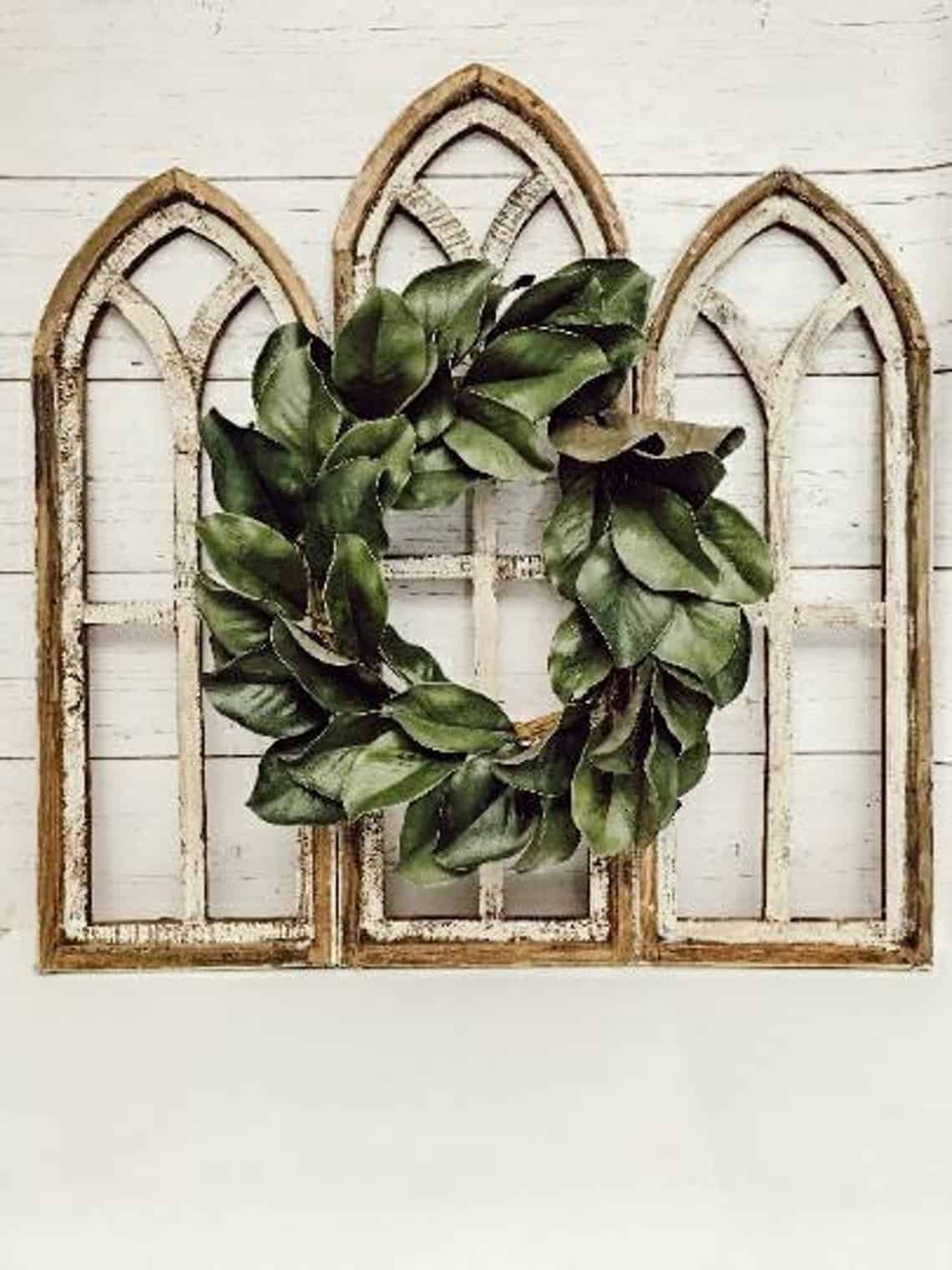 This gorgeous magnolia wreath mounted on chippy paint cathedral windows is perfect for decorating above the bed