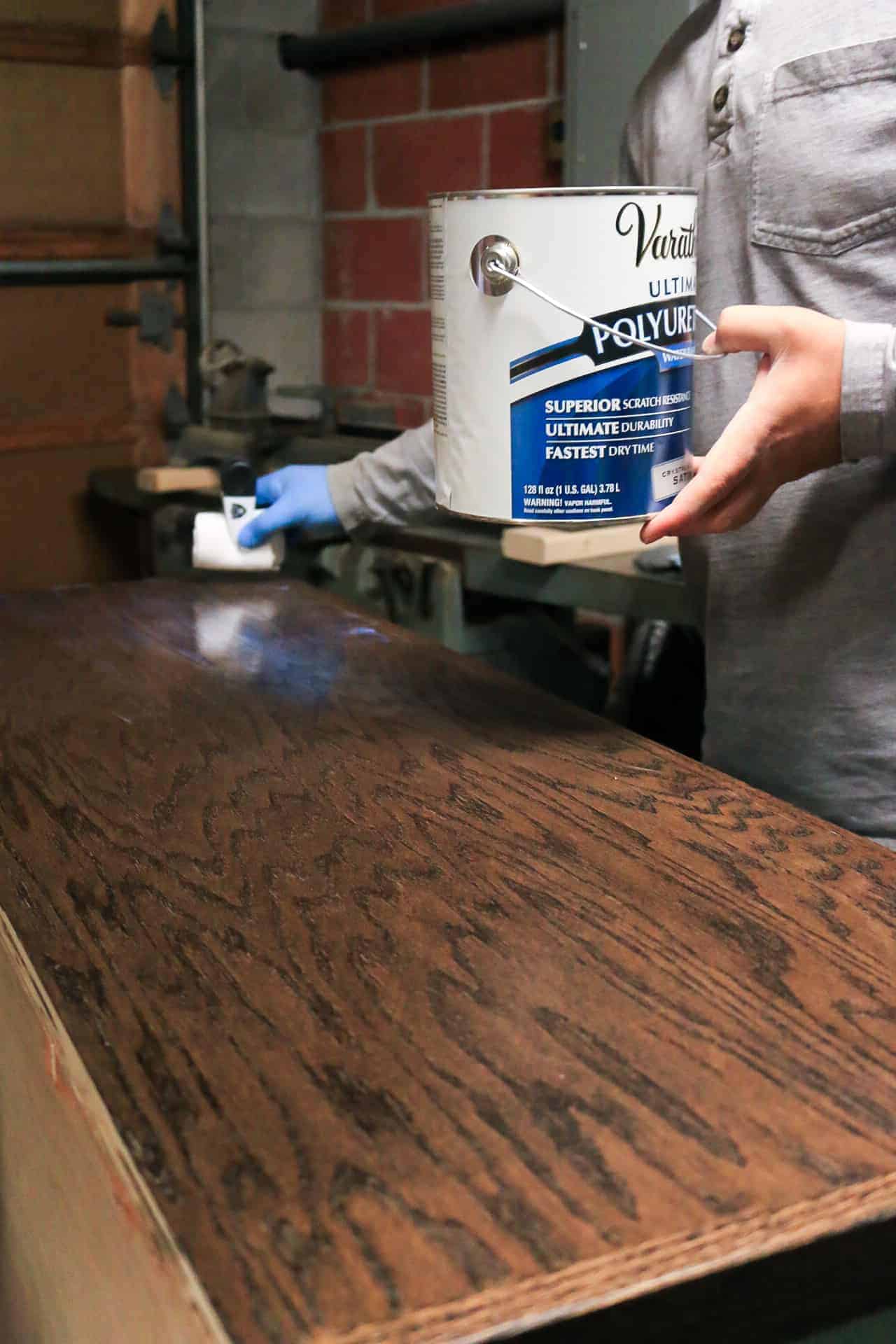 Applying polyurethane to the top of wood hallway cabinet countertop.