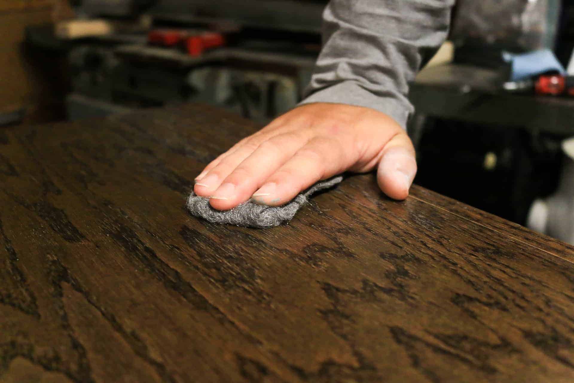 Using steel wool to sand down the layers of Polyurethane to give the hallway cabinet countertop a perfect finish.