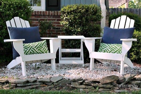 White restored Adirondack chairs sitting outside with blue and green throw pillows