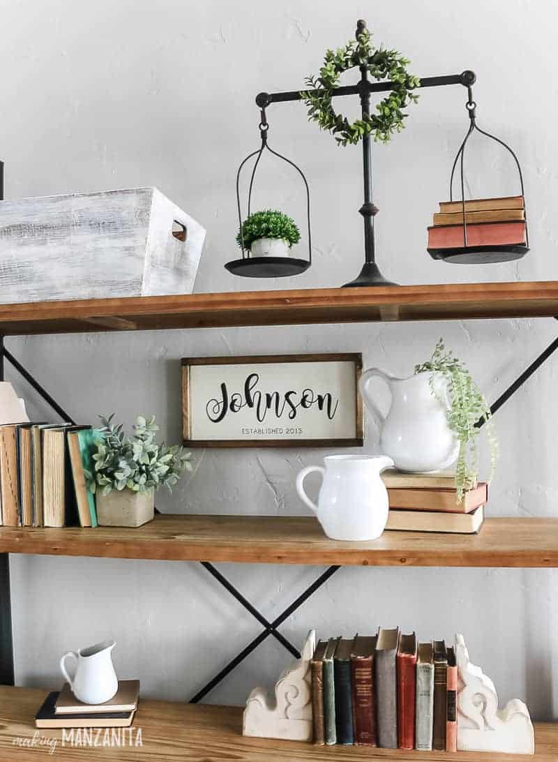 A look at all my bookshelf decor - vintage books between novelty bookends, stacked books, and white ceramic farmhouse style pitchers willed with cascading faux greenery.