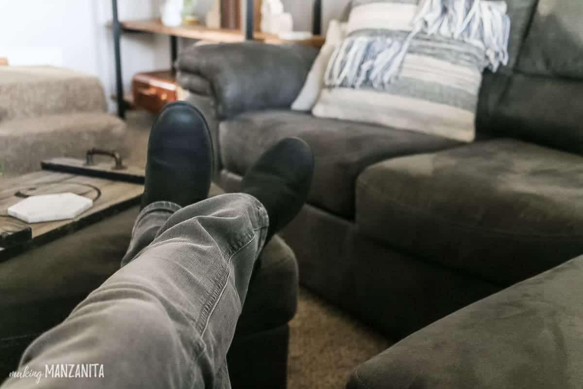 Feet lifted up on to a gray ottoman to show relaxing living room that is cozy
