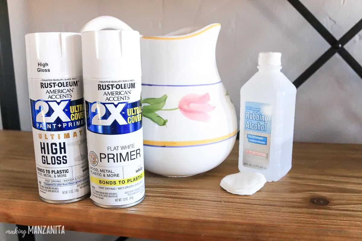 Supplies needed to make upcycled white farmhouse pitchers: 2 bottles of white spray paint, a thrifted white ceramic pitcher, and a bottle of rubbing alcohol