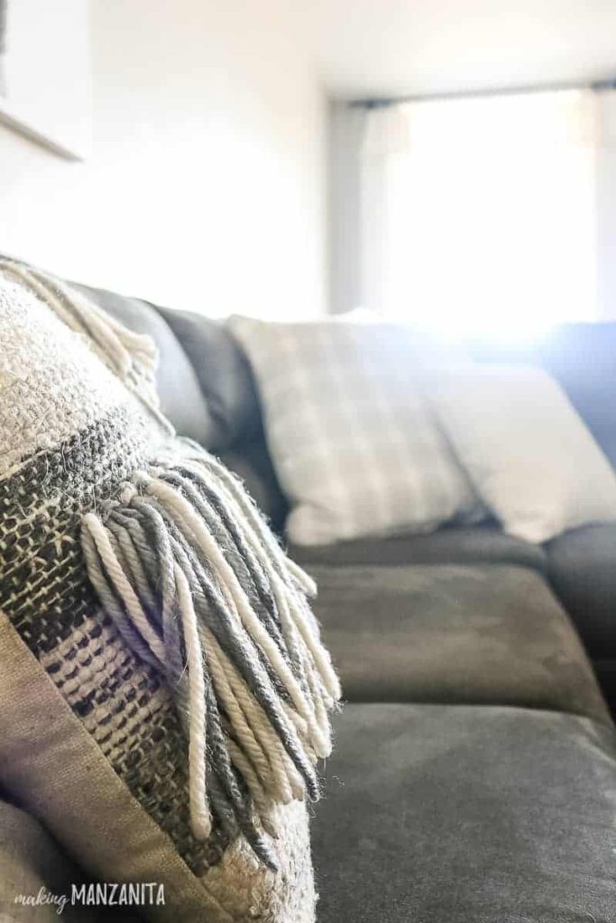 A textured pillow with yarn fringe that gives your fall decorations a cozy touch for Inexpensive Fall Decorating Ideas