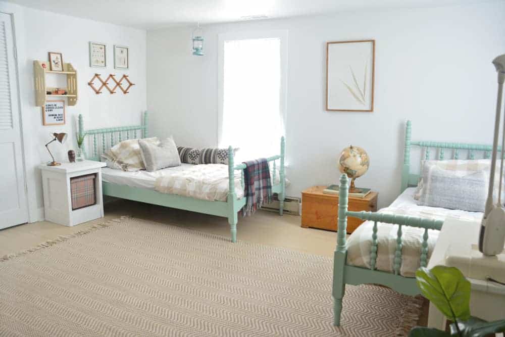 Vintage furniture painted mint green in a bedroom with two beds and other vintage decor pieces
