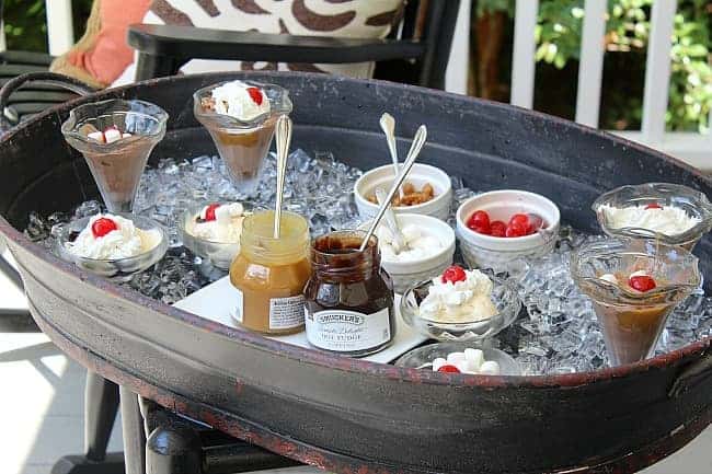 Ice cream sundae fixings in a metal tray cart with ice to keep cool on a porch